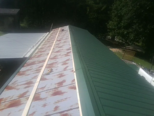 Old rusted panels beside newly installed green metal roofing — Wind Damage Roof Repair by Roofing Brothers in Luray