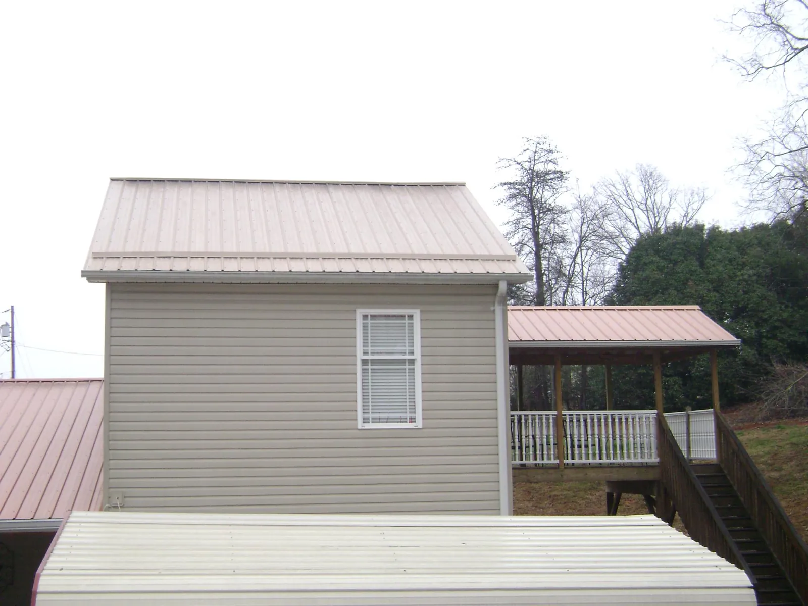 Tan metal roofs on a two story addition and attached porch, from a Roof Replacement job in Luray
